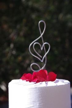 a white cake with red roses and a metal trellis on top that says love