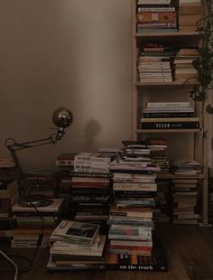 a pile of books sitting on top of a wooden floor next to a book shelf