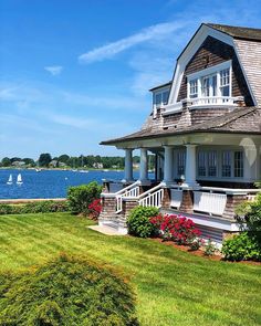 a large house sitting on top of a lush green field next to a body of water