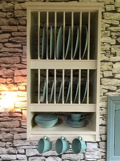 a shelf filled with plates and cups next to a stone wall