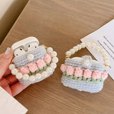 two small crocheted purses with pearls and beads on them, one being held by a person's hand