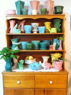 a wooden shelf filled with lots of colorful dishes and vases on top of it