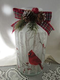 a glass vase with a cardinal and pine cones on it