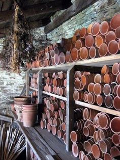 many clay pots are lined up on a shelf in a room with brick walls and ceilings