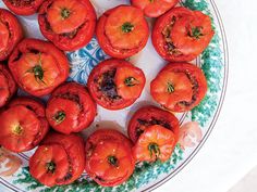 a plate filled with lots of red tomatoes on top of a table