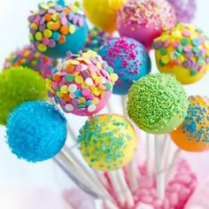 there are many colorful cake balls hanging from the ceiling and in front of a white background