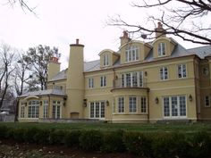 a large yellow house sitting on top of a lush green field