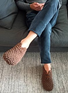 a woman is sitting on a couch with her feet propped up and wearing slippers