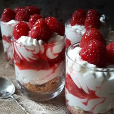 three desserts with raspberries and whipped cream in glass containers on a table