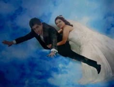 a bride and groom are floating in the air on their wedding day with blue skies behind them