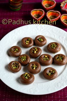 small chocolates with pistachio toppings on a white plate