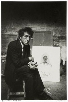 black and white photograph of a man sitting in front of an easel with a painting on it