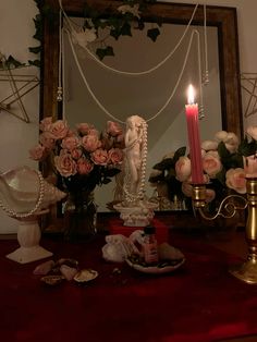 a candle is lit on a table with roses and other decorations in front of a mirror