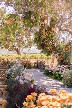 an outdoor ceremony area with flowers and lanterns hanging from the trees overhanging it