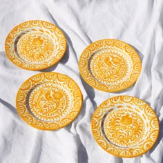 three yellow plates sitting on top of a white sheet