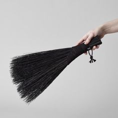 a hand holding a black long tassel