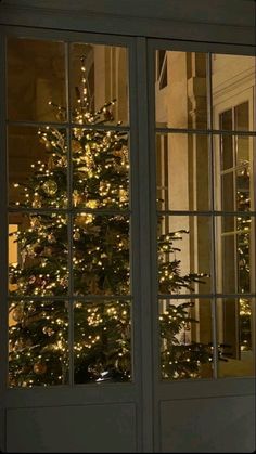 a lit christmas tree is seen through the window