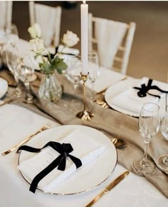 the table is set with white and gold plates, silverware, and black napkins