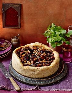 a table topped with a pie covered in toppings next to a potted plant