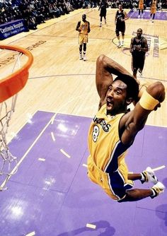 a basketball player dunks the ball in front of his head while others look on