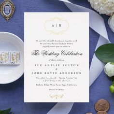 the wedding stationery is laid out on a blue table cloth with white flowers and coins