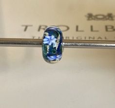 This Trollbeads charm is a rare find with its beautiful blue glass bead and silver metal. The charm is perfect for those who love beaded jewelry and want to add a unique piece to their collection. The blue flowers design adds a touch of elegance to the charm, making it a great addition to any bracelet or necklace. The charm is made with high-quality materials, ensuring its durability and long-lasting use. Get this Trollbeads charm today and add a stunning piece to your jewelry collection. Charm Making, Flowers Design, Blue Beads, Glass Bead, Beautiful Blue, Blue Glass, Blue Flowers, Flower Designs, Unique Pieces