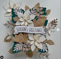 a christmas card made with paper flowers and ribbon saying season's greetings on it