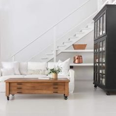 a living room filled with furniture and a stair case in front of a white wall