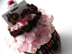 a cupcake decorated with pink and brown ruffles on top of a white table