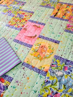 an elephant themed quilt is laying on the floor next to a purple and blue striped pillow