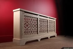 a large wooden cabinet sitting on top of a carpeted floor next to a red wall