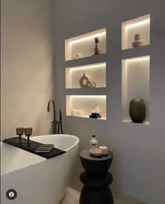 a white bath tub sitting next to a shelf filled with vases