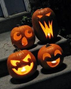 four carved pumpkins with faces on them sitting on the steps in front of a house