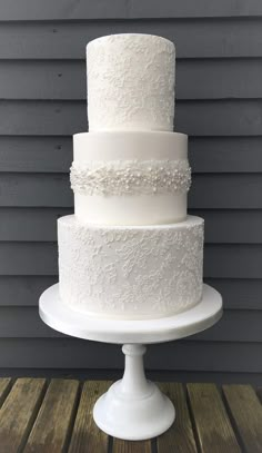 a white wedding cake sitting on top of a wooden table