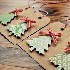 three tags with christmas trees on them sitting on a wooden floor next to twine string