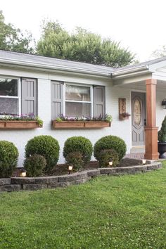 a white house with some plants in the window boxes on the front and side of it