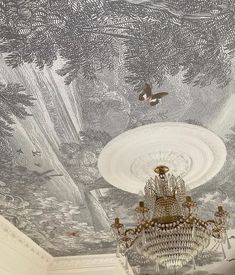 a chandelier hanging from the ceiling in front of a painting on the ceiling