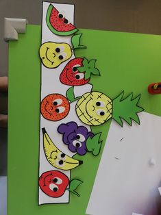 a paper cut out of fruit and vegetables on a green background with scissors next to it