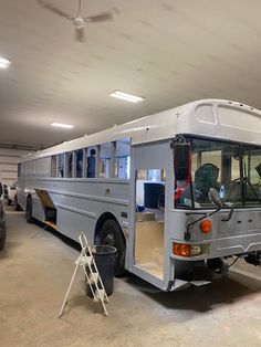 a silver bus parked in a garage next to other cars