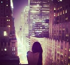 a woman standing on top of a tall building looking out at the cityscape