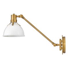 an antique brass wall light with a clear glass shade on the arm and back end