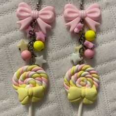 two candy lollipops with bows on them are hanging from chain necklaces