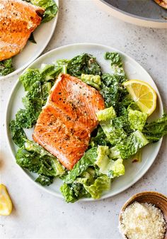 two plates with salmon, lettuce and lemon wedges