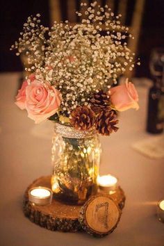 a vase filled with flowers sitting on top of a wooden slice next to two candles