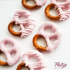 pink and brown donuts with frosting in the shape of o's on a white surface