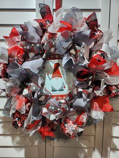 a christmas wreath with red, white and silver decorations on the side of a door