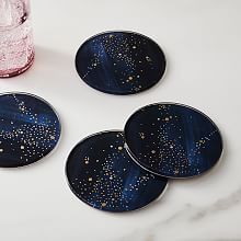 four blue plates with gold speckles on them next to a pink glass vase