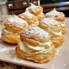 small pastries with powdered sugar on them are sitting on a white platter