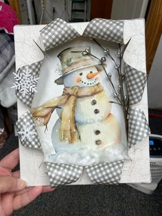 a hand holding up a snowman card