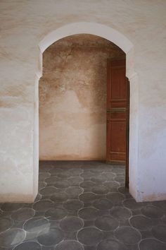 an open door in the middle of a room with stone flooring and arches on either side